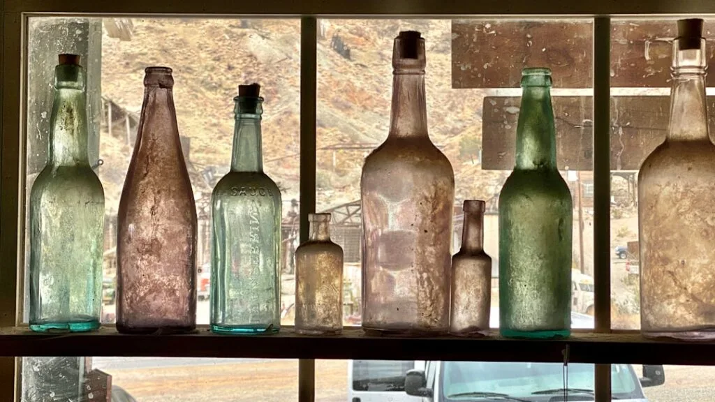 Bouteilles en verre ancien alignées sur rebord de fenêtre poussiéreuse