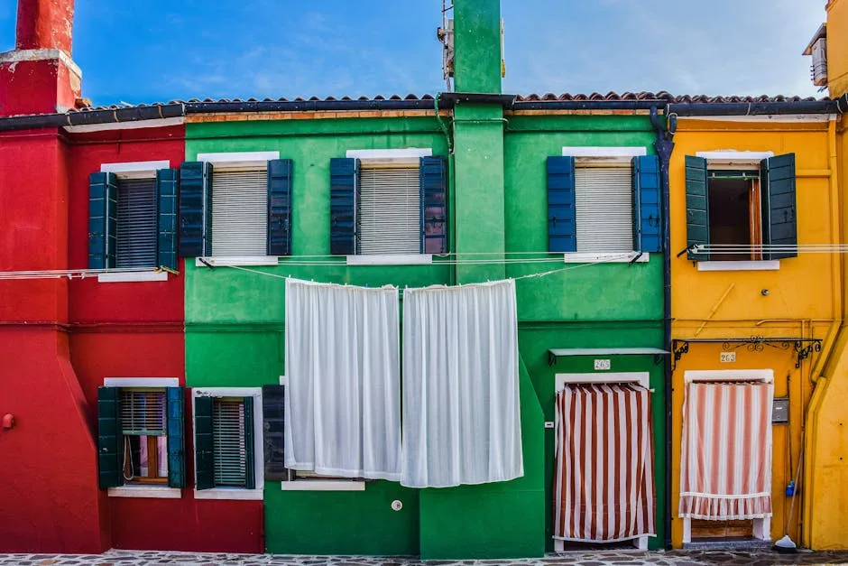 Façades rouges, vertes et jaunes de maisons à Burano avec linge qui sèche