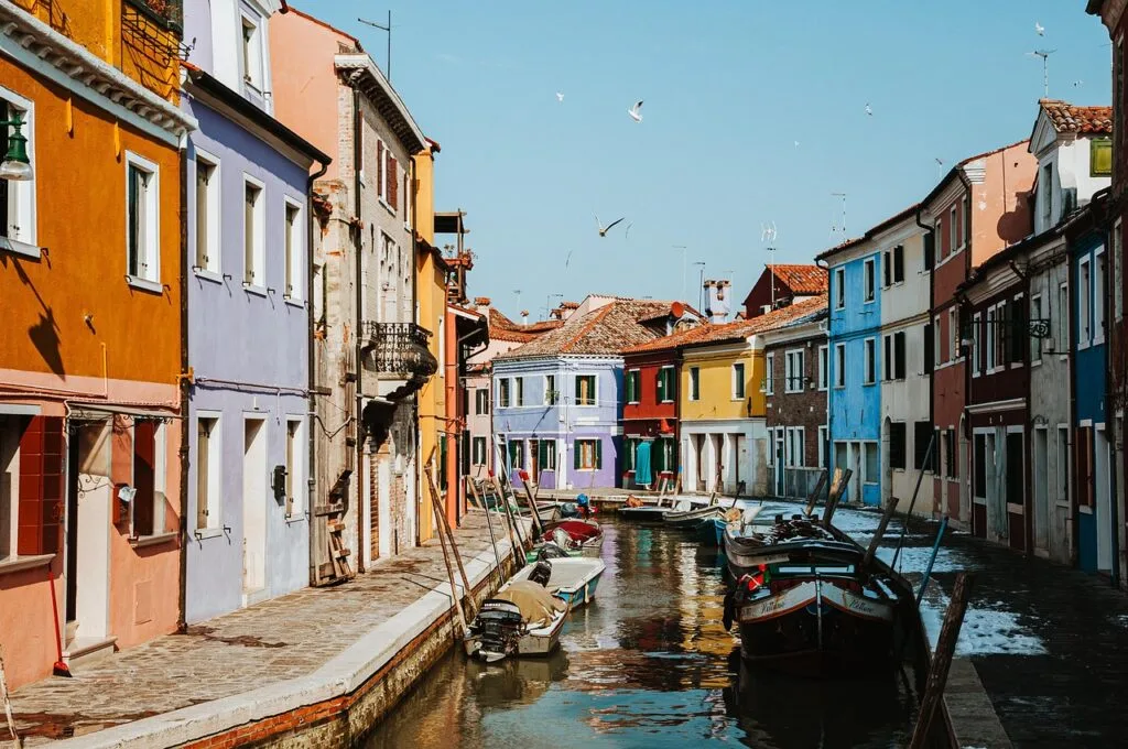 Canal bordé de maisons colorées et barques à Burano, Venise.