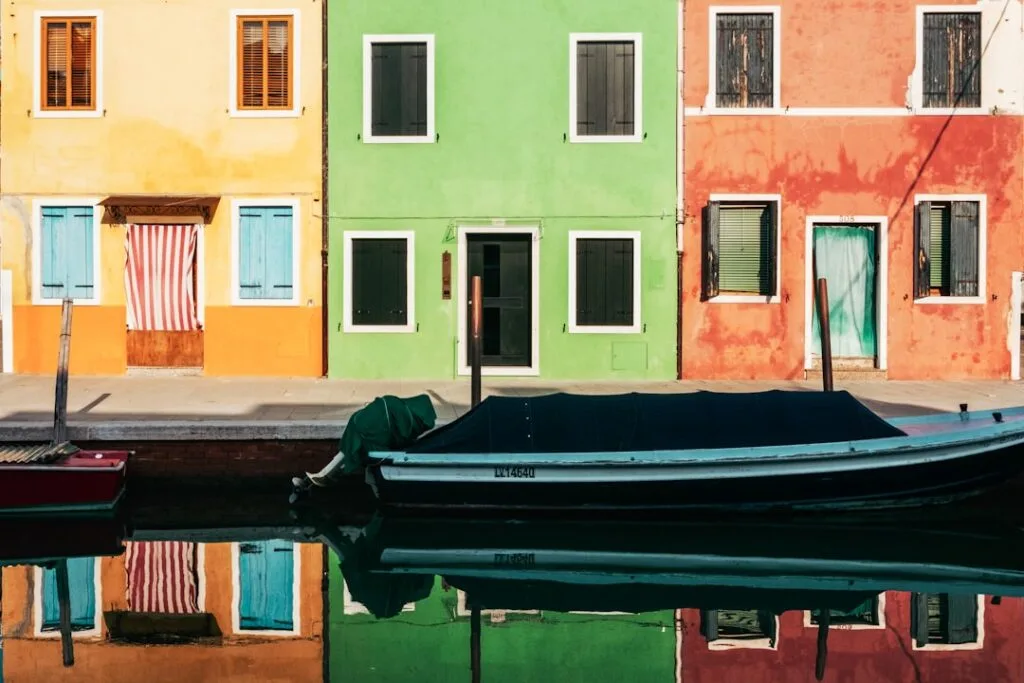 Bateau couvert amarré devant façades colorées reflétées dans le canal
