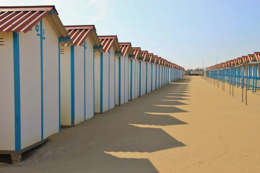 Beach cabins lined up on the Lido of Venice, shadows on the sand