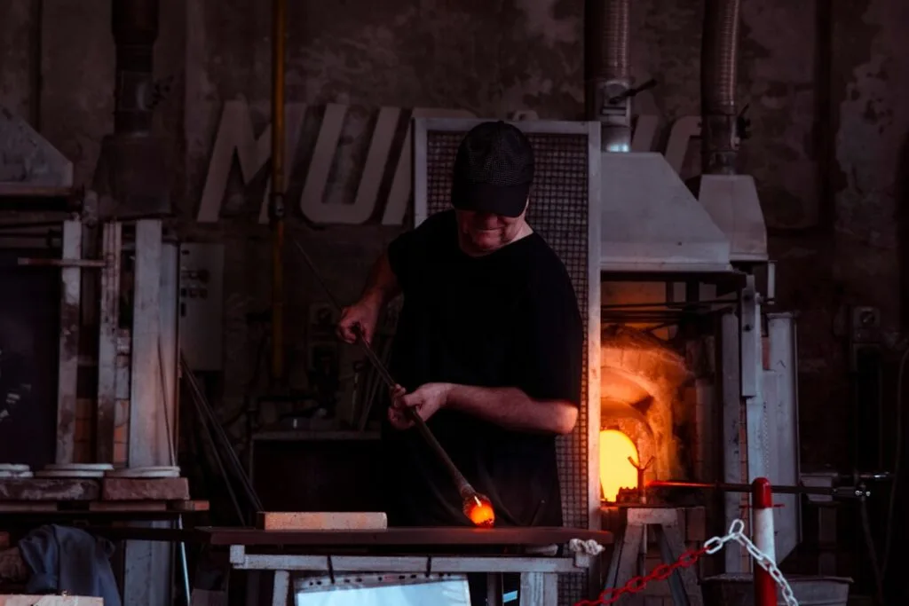 Souffleur de verre près d'un four incandescent dans un atelier de Murano