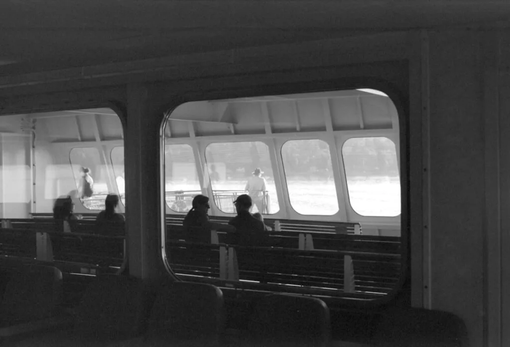 Silhouetten auf Bänken eines Vaporetto, Blick durch Fenster aufs Wasser in Venedig