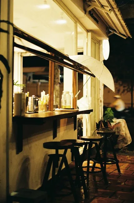 Petit comptoir de café à Venise, tabourets et parapluie accroché.