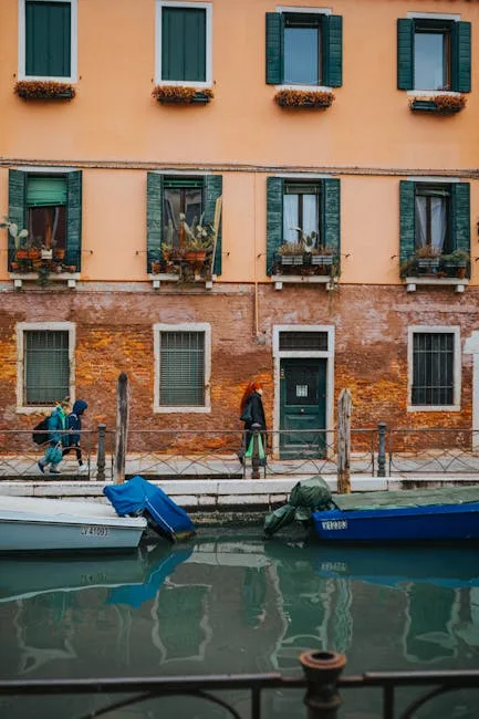 Façade orange à Venise avec volets verts, bateaux et passants sur canal