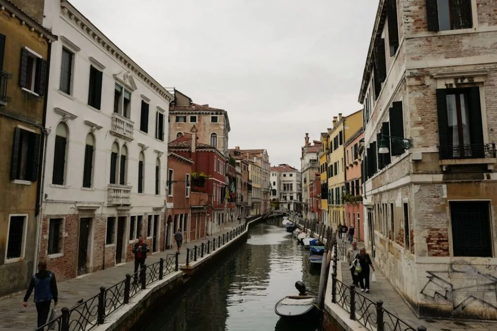 Petit canal vénitien bordé d'immeubles et de passants à Venise