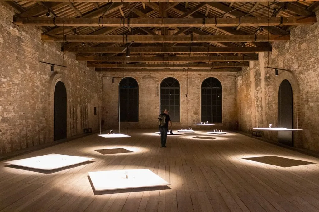 Salle d'exposition aux murs de brique, installation lumineuse dans l'Arsenale de Venise