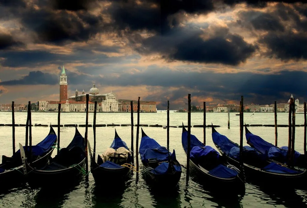 Gondoles amarrées aux pieux, ciel orageux et San Giorgio à Venise en arrière-plan