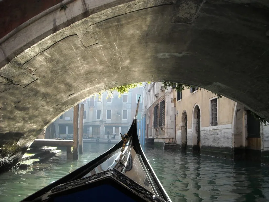 Vue depuis une gondole sous un pont étroit dans un canal vénitien
