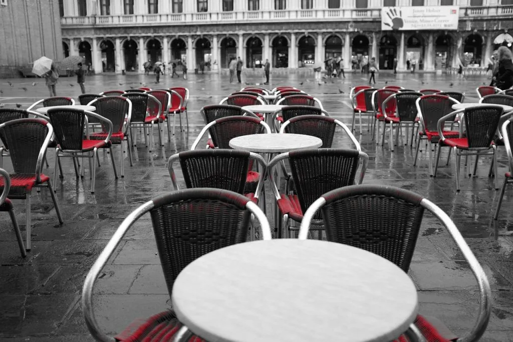 Chaises rouges vides sur sol mouillé de la place Saint-Marc, Venise.