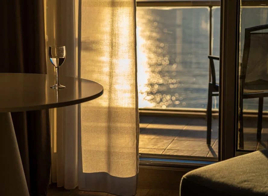 Verre posé sur une table, rideau et reflet de l'eau vus depuis Venise