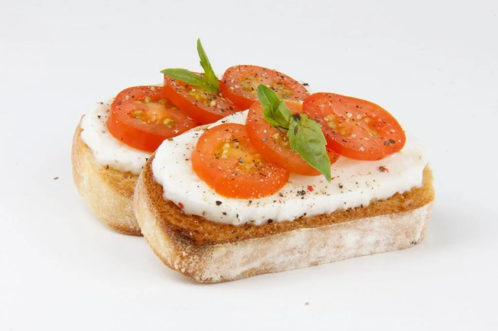 Deux crostini garnis de mozzarella, tomates cerises et basilic