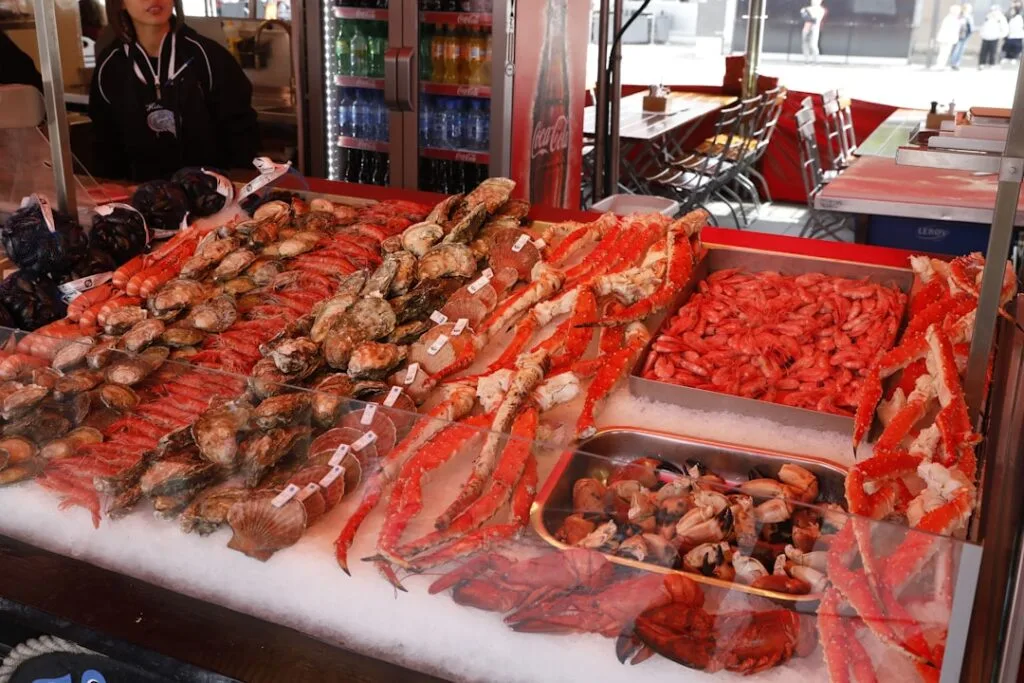 Crab legs, oysters and shrimp arranged on ice at Venice market stall.