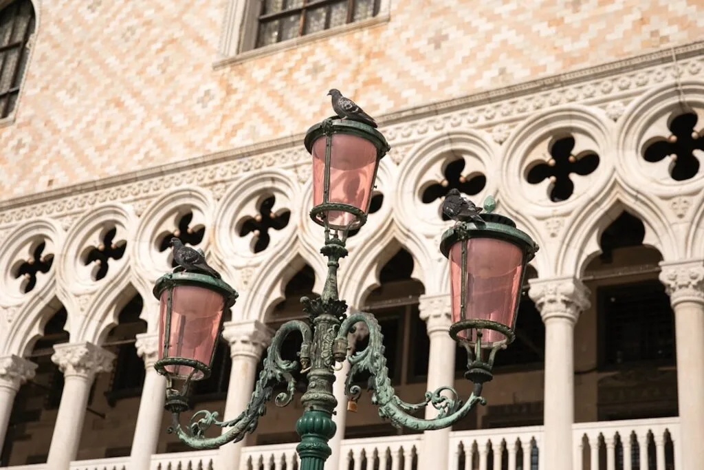 Lampadaires roses ornés de pigeons devant le Palais des Doges à Venise
