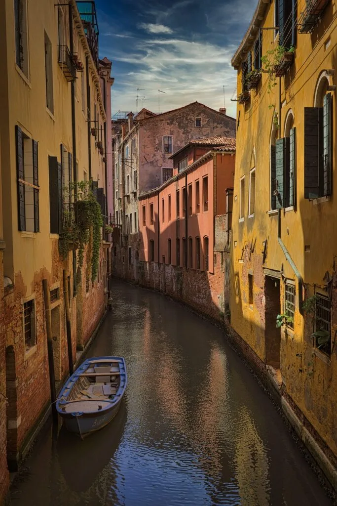 Ruelle d'eau à Venise encadrée de maisons jaunes et d'une barque.