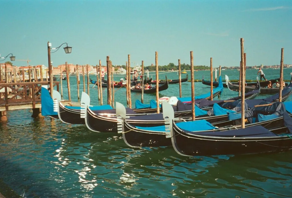 Reihen von Gondeln am Anleger vor venezianischer Lagune bei Sonnenschein